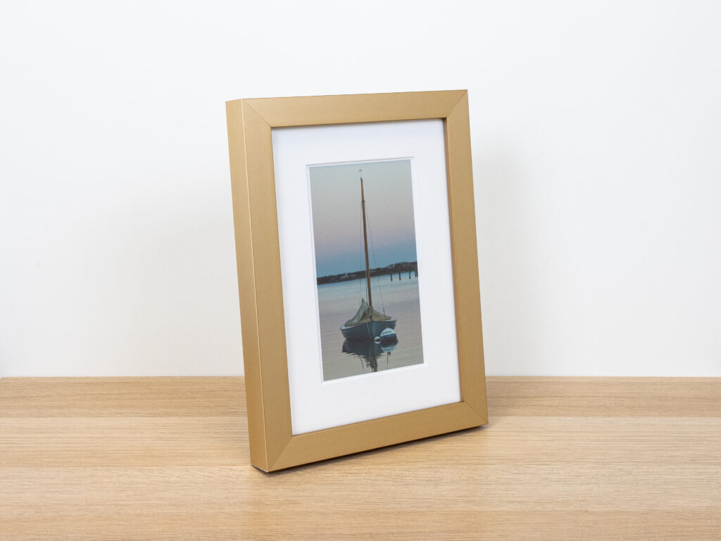 Photo of sailboat, matted, and framed in antique gold metal.